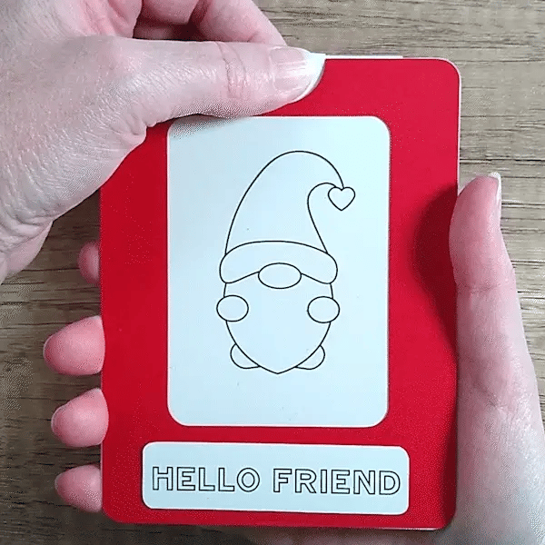 Hand pulling tab on a red framed Magic Slider Card with a gnome design and 'Hello Friend' text.