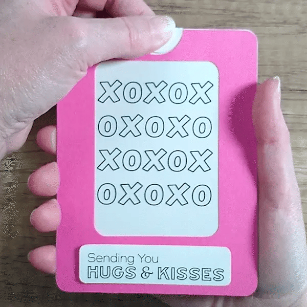 Pink Magic Slider Card with 'XOXO' text and 'Sending You Hugs & Kisses' message held by a hand.
