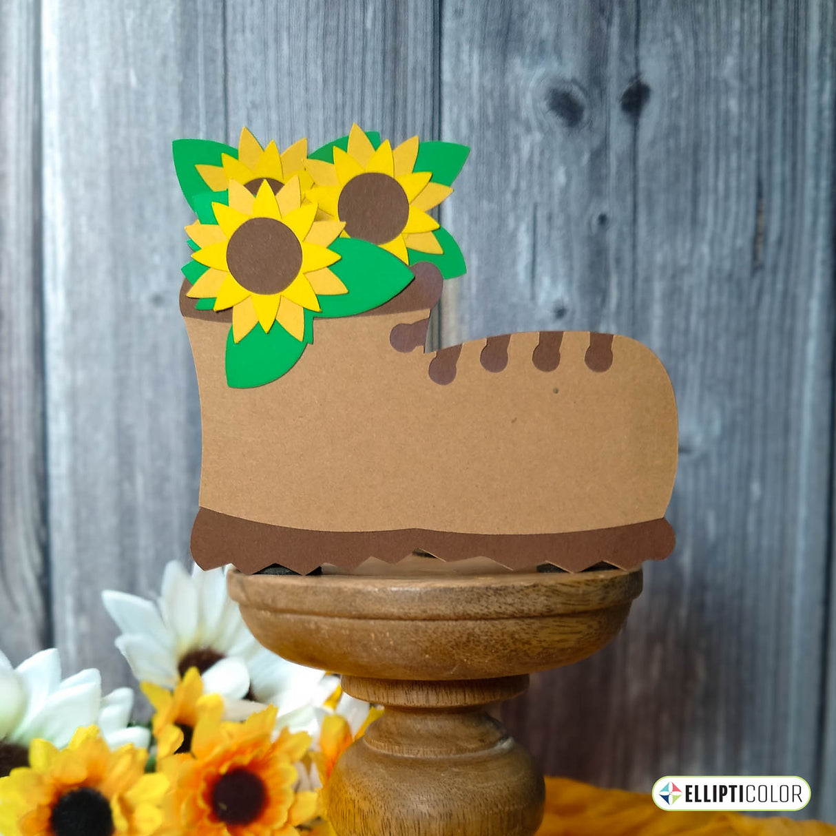 Sunflower Boot Box Card on pedestal, above sunflowers and in front of wood fence.