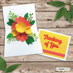 A Mother's Day greeting card with pop-up red and yellow flowers inside sitting on a wood background