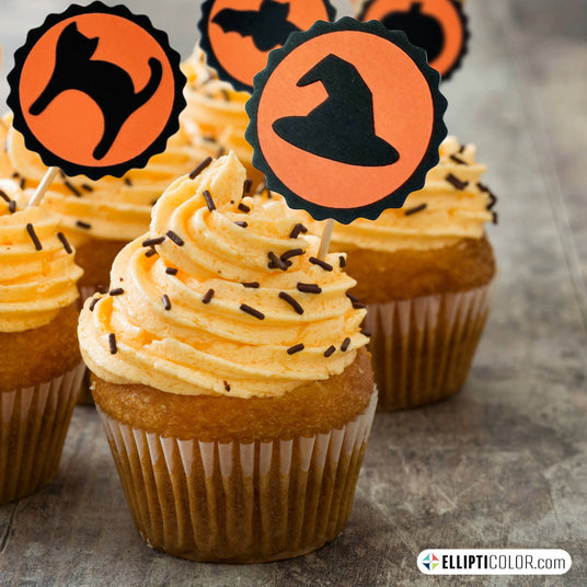Halloween-themed cupcakes with orange frosting and decorative toothpick toppers featuring  a witch hat, cat, bat, and pumpkin.