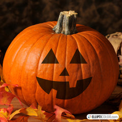 Jack-O'-Lantern face stickers on a pumpkin, autumn leaves, and a dark background