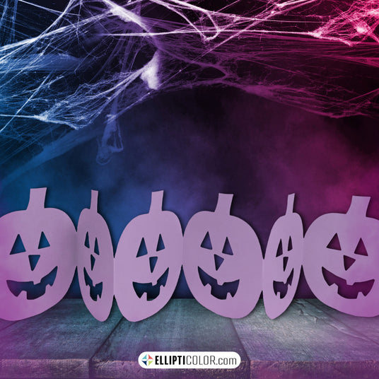 Purple Jack-O'-Lantern cutout table garland with spider webs and a dark, misty background